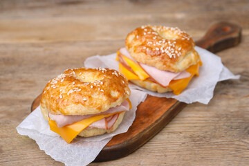 Delicious bagels with ham and cheese on wooden table