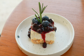Blueberry cheesecake on white plate. Enjoy fresh baked dessert in Coffee Shop. Closeup shot of little sweet decorative cake.