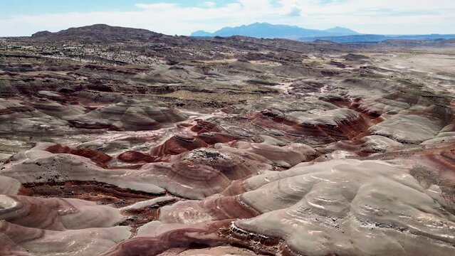 Aerial-Descending over the beautiful multicolored layers Bentonite Hills-Distant mountain in the background.