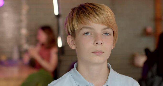 Close portrait of young guy teenager boy indoors. Student Person silent focused gaze into the camera portrays moment of deep reflection, self-awareness, contemplation. People Poses, lifestyle.
