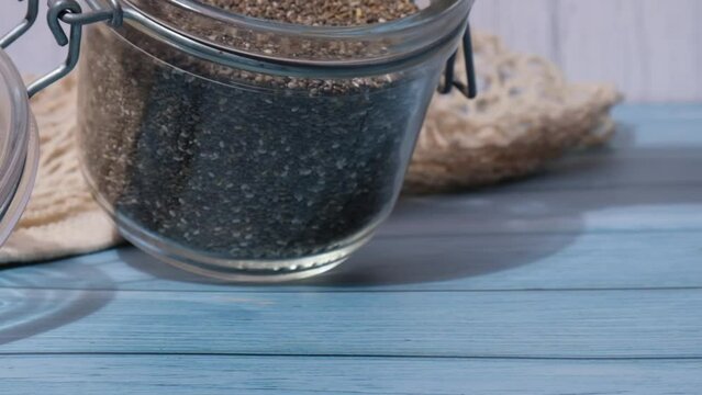 Slow motion chia seeds fall from glass jar. Healthy superfood rich in Omega 3 fatty acids. Dry healthy natural ingredient. Chia grains are falling. Vegetarian food 