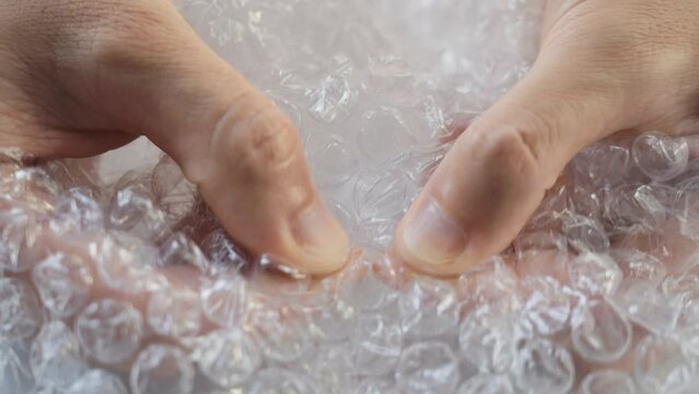 Nervous woman press plastic bubble wrap as a stress relief. Woman's hands pressing hard on a bubble wrap