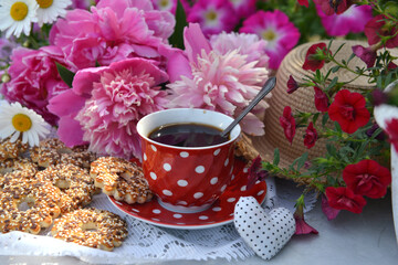 Beautiful still life with peony flowers, vintage cup and cookies on the table. Romantic greeting card for birthday, Valentines, Mothers Day concept. Summer background with vintage objects