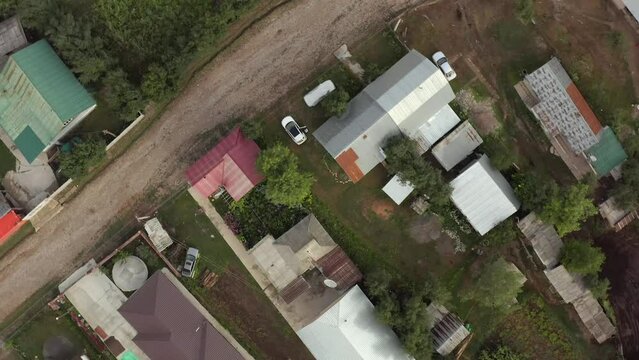 Spinning down drone view traditional Arkit village highlands on summer day in mountain. Homes and cars in near mountains.