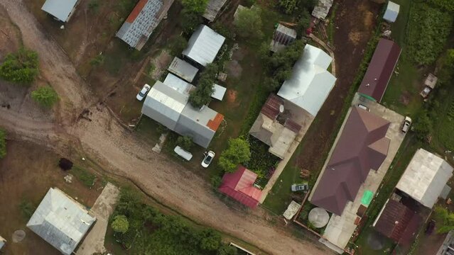 Village top view. Traditional Arkit village highlands rotating down drone shot, homes roof and cars on sunny day in mountain.
