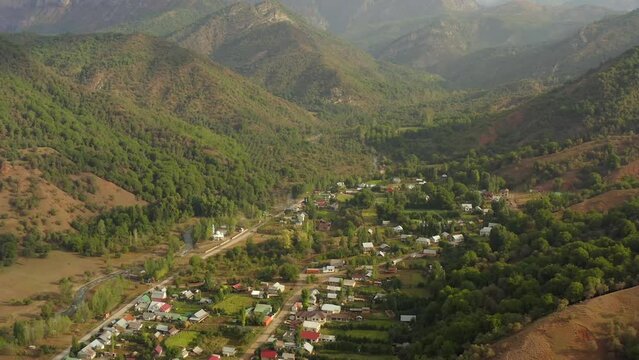 Aerial shot landscape of Kyrgyzstan traditional Arkit scenic village in mountains. Bird's eye view of a settlement located in highlands.