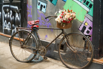 Bicycle adorned with a lovely bouquet of poppies against a wall.