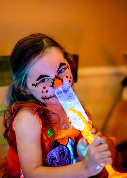 Kid drinking potion on Halloween scarecrow makeup  face paint glowing in black light