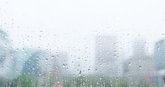 City, window with rain and water on glass in office, building or urban apartment in London or winter, weather or storm. Blurred background, view and rainfall with fog or wet moisture and mist
