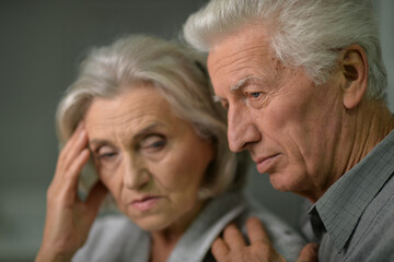 Close up portrait of sad senior couple posing at home