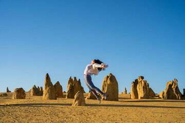 Tourist jumping in joy at The Pinnacles desert in Western Australia.