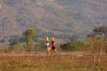 Two girls carrying gallons of Water on their heads in a water-scarce region