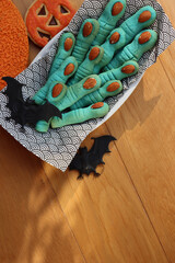 Blue Witch’s fingers cookies for Halloween on a plate on wooden table with decorations 