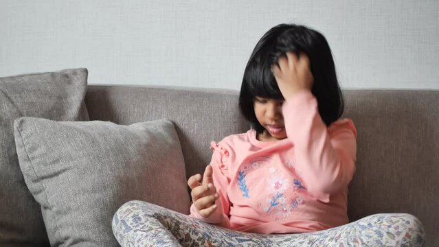  child itchy scalp and hair sitting on sofa ,