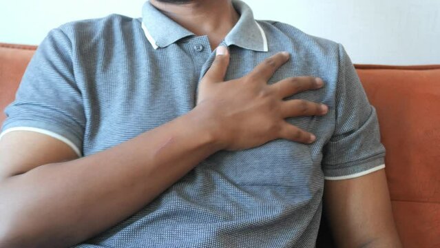 young man suffering pain in heart and holding chest with hand 