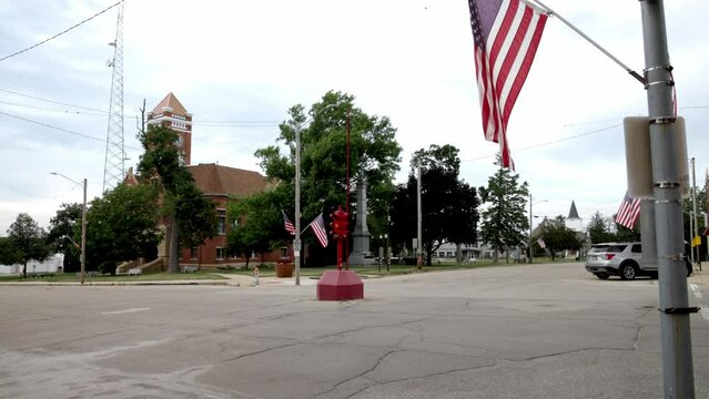 Antique four way stop light and American flag in downtown Toledo, Iowa with stable video wide shot at an angle.