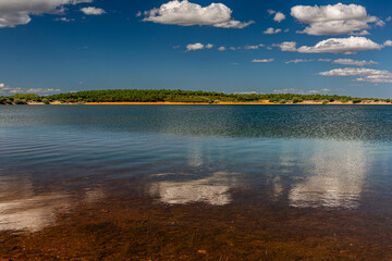 Tabuyo del Monte reservoir, pine forest and blue sky with clouds, Leon, Spain.