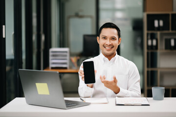 Confident Asian man with a smile standing holding notepad and tablet at the office.