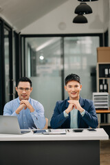 Two Asian business workers talking on the smartphone, tablet and using laptop at the office.
