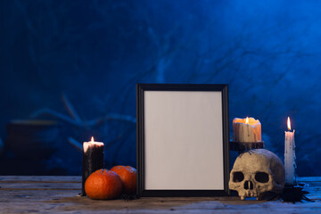 Black frame with copy space, skull, candles and smoke on blue background