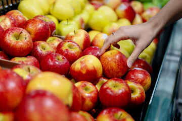 Close up hand picking red apples in the shelf.