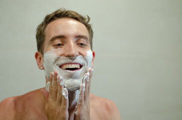 Young man having fun applying shaving cream to his face