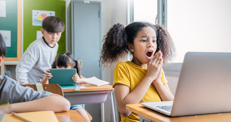 Pupil black girl learn computer in classroom at elementary school. Student girl studying in primary school. Stressful children use laptop in classroom. Education knowledge online digital technology