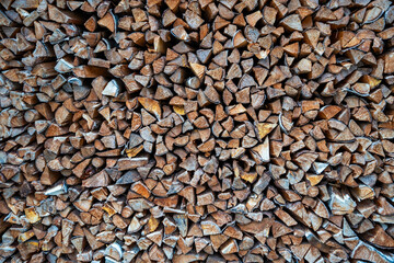 Background of stacked chopped wood logs. Pile of wood logs ready for winter. Wooden stumps, firewood stacked in heap 