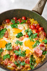 Shakshouka for breakfast. Homemade shakshuka, fried eggs, onion, bell pepper, tomatoes and parsley in a pan. Marble background. Top view. chakchouka