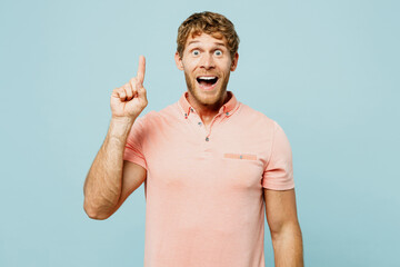 Young proactive caucasian blond man wear pink t-shirt casual clothes holding index finger up with...