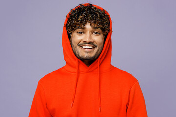 Close up young unshaven cool student Indian man in hood wear red orange hoody casual clothes look camera isolated on plain pastel light purple color wall background studio portrait. Lifestyle concept.
