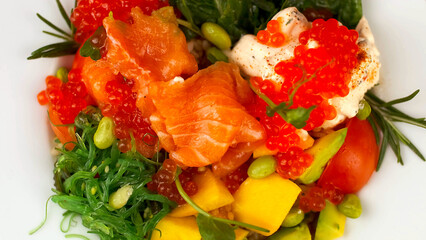 Poke bowl with fresh salmon, chukka salad, beans and caviar. A plate of healthy food on a light background.