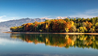 Panoramic autumn landscape. Colorful trees, lake and mountains at background