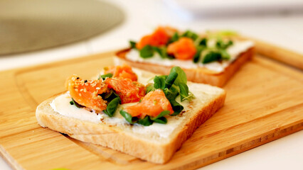 Breakfast toast with cream cheese, salmon and avocado and cherry tomatoes. the concept of healthy eating and healthy lifestyle. cooking sandwiches with fillet of red fish.
