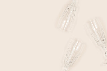 Crystal glasses scattered on a beige background. Creative concept with copy space.