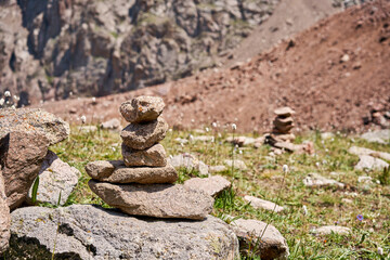 Fototapeta na wymiar Zen balanced stones stack in high mountains. Pyramidal of stones against the backdrop of a picturesque mountain valley. Moraine in the highlands of Kazakhstan.