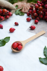 Berries of rosehip in a wooden spoon. Healthy ingredient. Alternative medicine and herbal therapy concept. Side view.