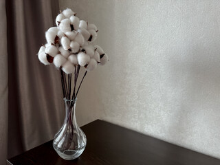 on the chest of drawers you will dig up there is a bouquet of white cotton flowers in a glass vase