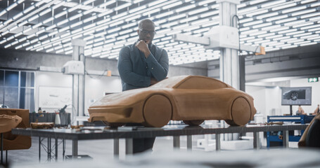 Portrait of a Handsome Automotive Designer Developing a 3D Clay Model of a New Production Car. Professional Black Man Looking At Finished Prototype of Concept Car, Thinking About Improvements.