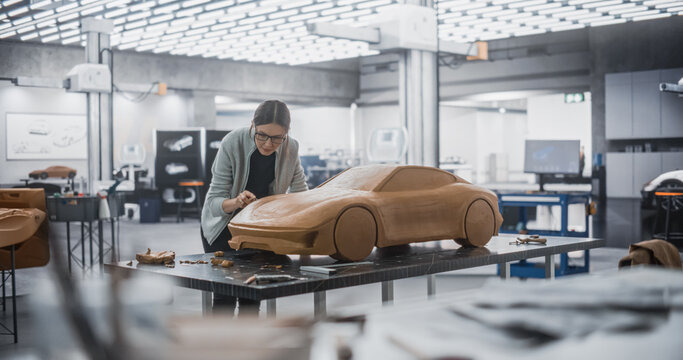 Automotive Artist Making Final Strokes on Her Latest Concept Car Creation. Enthusiastic Female Designer Working on a New Prototype, Sculpting Industrial Plasticine Clay 3D Model of a Sporty Coupe.