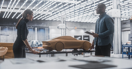Enthusiastic Teamwork of Two Diverse Creative Colleagues Working in Automotive Development Design Agency. Professional Sculptor Working Together with an Engineer, Discussing the Prototype Vehicle