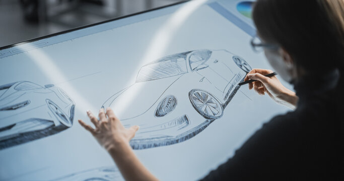 Female Car Designer Using a Digital Tablet to Draw a Prototype Car Sketch with a Stylus. Talented Industrial Artist Working in a Research and Development Studio at a Vehicle Production Factory