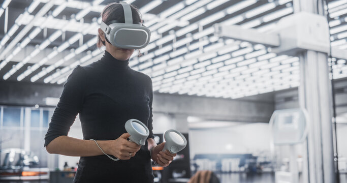 Female Specialist Using a Virtual Reality Headset and Controllers at Work in a Technology Research and Development Office. VR Software Engineer Programming a Virtual Game or Augmented Reality Solution