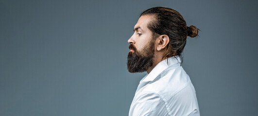 Side view bearded man isolated on gray background. Man's haircut in barber shop. Side view portrait of stylish young man. Perfect beard. Close-up of young bearded man, stylish hairstyle, beard