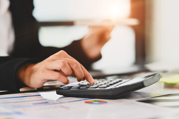 Closeup female accountant using calculator, checking finances, counting bills or taxes at desk.