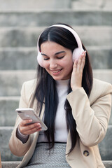 girl with shopping bags on the street listening to music with headphones and calling on the phone and sending messages