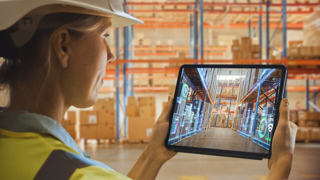 Futuristic Technology Warehouse: Female Worker Doing Inventory, Using Augmented Reality Application On Tablet. Digitalization Process Analyzes Products Delivery Infographics in Distribution Center - Powered by Adobe