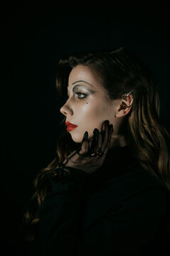Portrait of a young woman in a Gothic gloomy image of a witch or vampire. Halloween costume. Vertical photo.