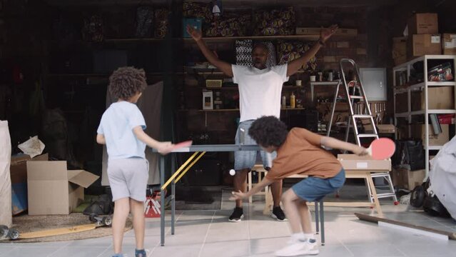Multi Ethnic Young Boys Playing Table Tennis While Black Dad Supports