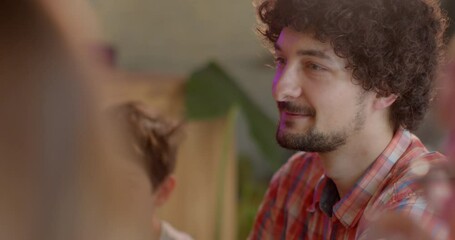 Close portrait of young curly man during a conversation. Involuntary laughter or smiling as psychological defense mechanism. Laughter can help build rapport and trust between therapist and client.